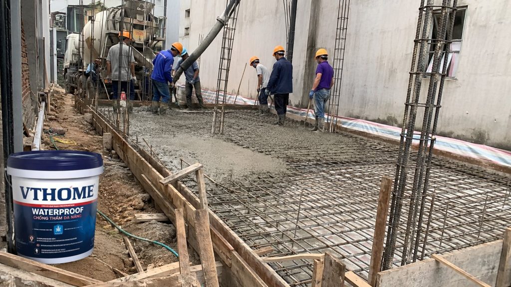 Công trường thi công móng nhà phố: thép móng, đà kiềng, cốp pha và thợ đổ bê tông, cạnh thùng chống thấm VTHome